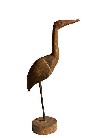 Sculptural and decorative bird carved from wood and standing on a wooden stand.