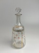 Beautiful, small, antique carafe in clear glass. 
Decorated with enamel paint in white, yellow and 
gold with motif of daisies