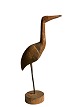 Sculptural and decorative bird carved from wood 
and standing on a wooden stand.